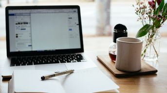   a computer, notebook, and teacup