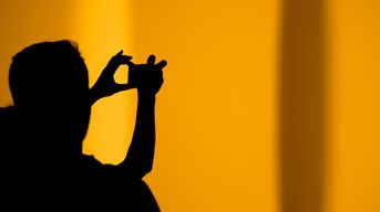 Shadow of a man holding a camera on an orange background 