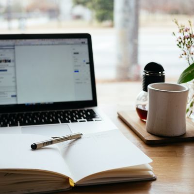   a computer, notebook, and teacup